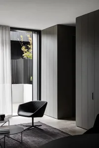 A modern living room featuring sleek black furniture, concrete flooring, and a large window with natural light.
