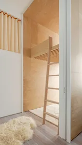 A minimalist bedroom featuring a wooden bunk bed with a ladder.