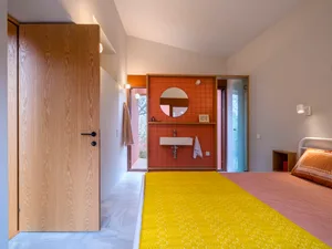 A minimalist bedroom featuring yellow fabric, orange tiles, and white marble.
