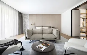 A modern minimalist living room with a grey sofa, white armchairs, and a round coffee table.