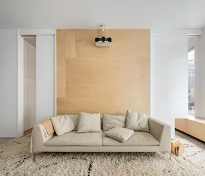 Modern living room with minimalist design, white sofa, wood-paneled wall, and modern projector setup.