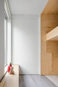 A minimalistic bedroom featuring wooden paneling and a large window with natural light.