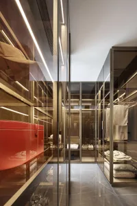 Modern walk-in closet with glass cabinets and marble flooring.