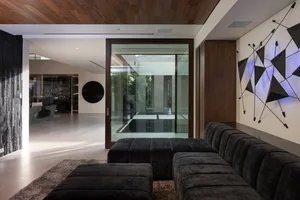 Contemporary living room featuring black leather furniture, metal elements, and a geometric wall art installation.