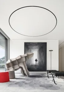 A modern minimalist interior design featuring a sleek, geometric sculpture and a patterned rug, with a large circular light f