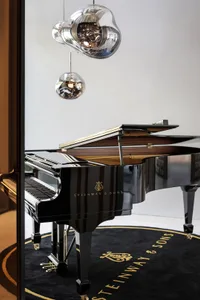 A modern music room featuring a black Steinway & Sons piano, complemented by contemporary pendant lights.