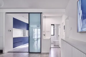 Modern kitchen with white countertops, blue cabinets, and glass sliding door.