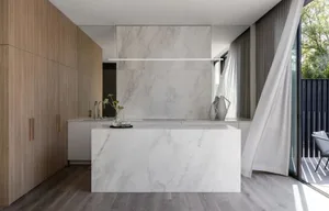 A modern kitchen with a marble countertop and wooden cabinets.