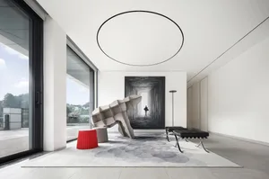 A modern living room featuring minimalist design with concrete flooring, large windows, and a unique sculptural furniture pie