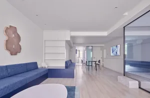 A modern living room with white walls, blue sofa, and minimalist decor.