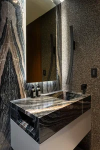 A luxurious modern bathroom with a marble sink, mirror, and walls.
