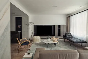 A living room with a modern minimalist design featuring a large sofa, coffee table, and television unit.