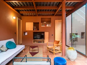 A minimalist living room with wooden furniture and minimalist decor, featuring a grey sofa, wooden armchair, terracotta tiles