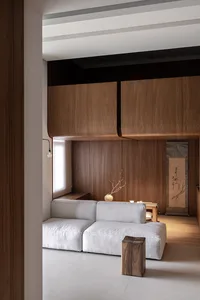 Minimalist living room featuring a modern sofa, wooden cabinets, and a traditional painting.