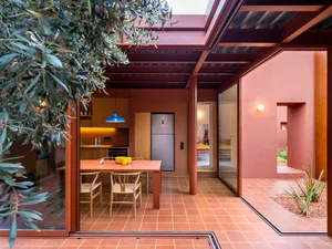 Modern residential design featuring a kitchen dining space with a terracotta floor and heavy metal accents.