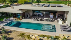 Modern residential outdoor space featuring a swimming pool with concrete and glass elements.