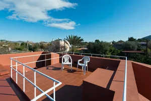 Modern rooftop patio with concrete flooring and white chairs.