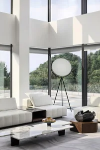 Modern white leather furniture with marble coffee table and large floor lamp in a spacious living room with floor-to-ceiling 