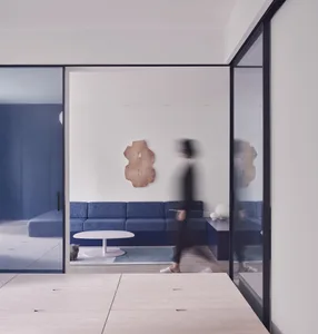 A minimalist living room with a blue fabric couch, modern coffee table, and abstract art on the wall.