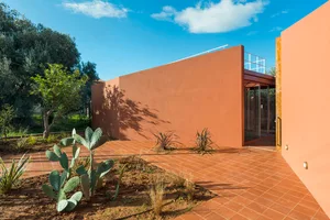 A modern exterior building with a combination of earth-toned concrete walls and a terracotta tiled landscape.