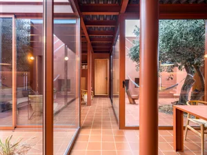 A modern patio house extension featuring a terrazzo floor, concrete columns, and large glass doors.