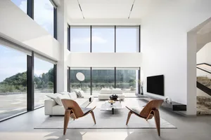 A spacious modern living room featuring minimalist decor and steel and glass elements.