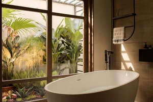 A minimalist bathroom featuring a freestanding bathtub with a serene indoor garden visible through the large window, providin