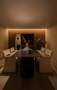 A modern interior space featuring a wooden table with white chairs, a vase of flowers, and a book.