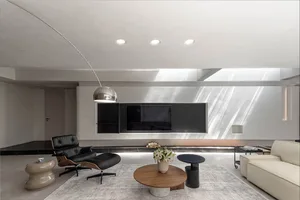 Modern minimalist living room featuring concrete walls, a white rug, and concrete furniture.
