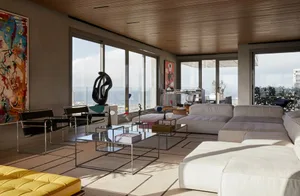 A modern concrete living room with large windows and a comfortable seating area, featuring a sleek coffee table and abstract 