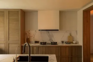 Modern residential kitchen featuring marble countertops and wooden cabinetry, with a minimalist design.