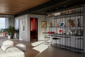 A modern living room with a concrete wall, a bar counter, and a lounge area.