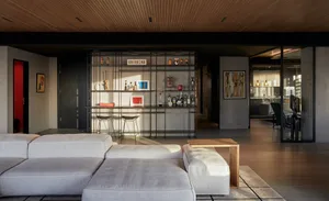 A modern living room featuring a bar area with metal and glass shelves, containing various decorative items, and a wooden cof