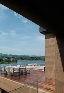 Modern outdoor deck featuring wooden flooring and concrete elements with a scenic lake and mountain view.