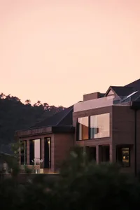 A modern residential building featuring glass, wood, and metal materials.