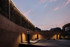 Modern rooftop garden with concrete and stone elements at dusk.