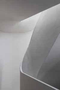 Modern architectural staircase featuring curved concrete design and white walls.
