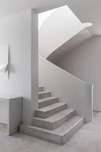 A modern, minimalist concrete staircase with a sleek, curved design.