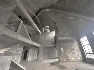Unfinished interior space with concrete walls and stairs in a building under construction or renovation.