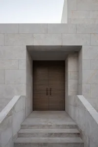 A modern doorway with marble steps and a wooden door.