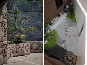 A modern garden featuring stone pathways, plants, and a rock wall.