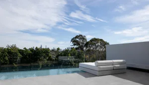 A modern outdoor living space featuring concrete and glass elements.