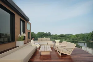 A minimalist terrace lounge featuring a wooden platform with outdoor furniture and a view of a serene lake.