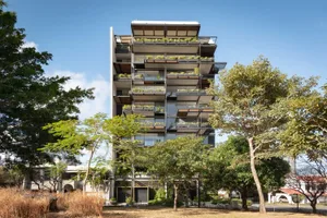 Modern residential apartments featuring glass balconies, steel frame, and lush greenery.