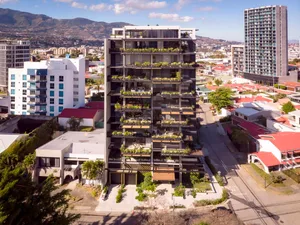 A modern apartment building featuring glass balconies overlooking a cityscape.