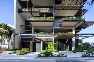 A modern building with concrete facade and greenery on balconies.
