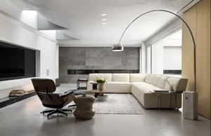A modern living room with a white sectional sofa, a wooden lounge chair, and a concrete floor.