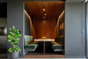 A modern restaurant interior featuring wooden accents on the booth seating and wooden table.