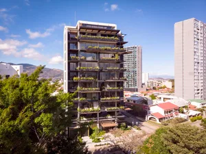 Modern apartment building with glass façade and green plants on balconies