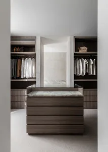 A modern walk-in closet featuring wall units with marble tops and dark wood finishes.